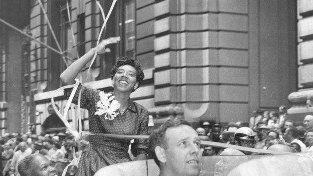 Althea Gibson waves from an open car during a victory parade in New York, 1957.